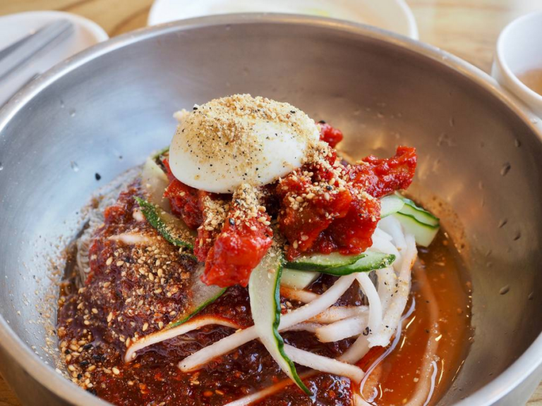 A bowl of mul naengmyeon with buckwheat noodles, sliced cucumber, boiled egg, and icy broth served at a naengmyeon restaurant in Seoul